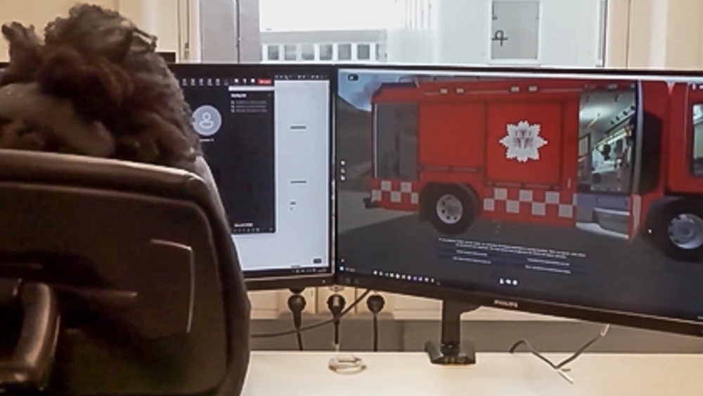 Bilde av en person som sitter foran to PC-skjermer med brannbiler på