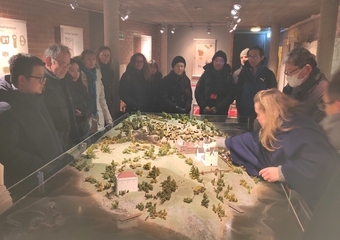 A group of people looking at a miniture landscape of Hamar in the 14th century