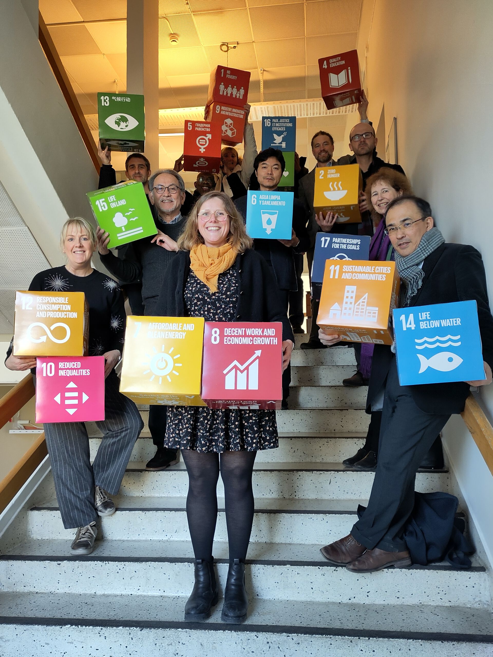 Gruppemedlemmer står i trappen og holder FNs bærekraftsmål