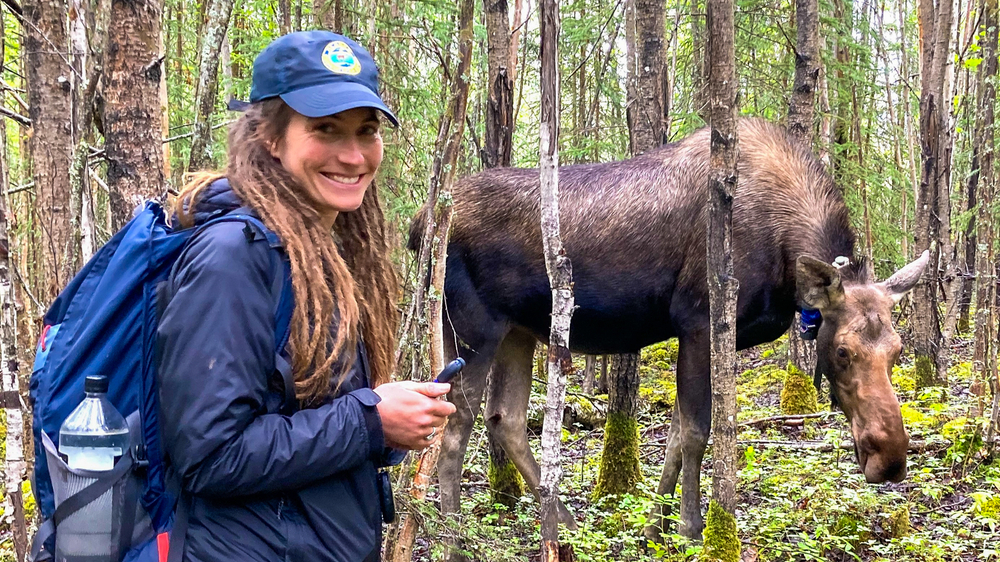 Picture of Theresa in a forest in front of a big moose