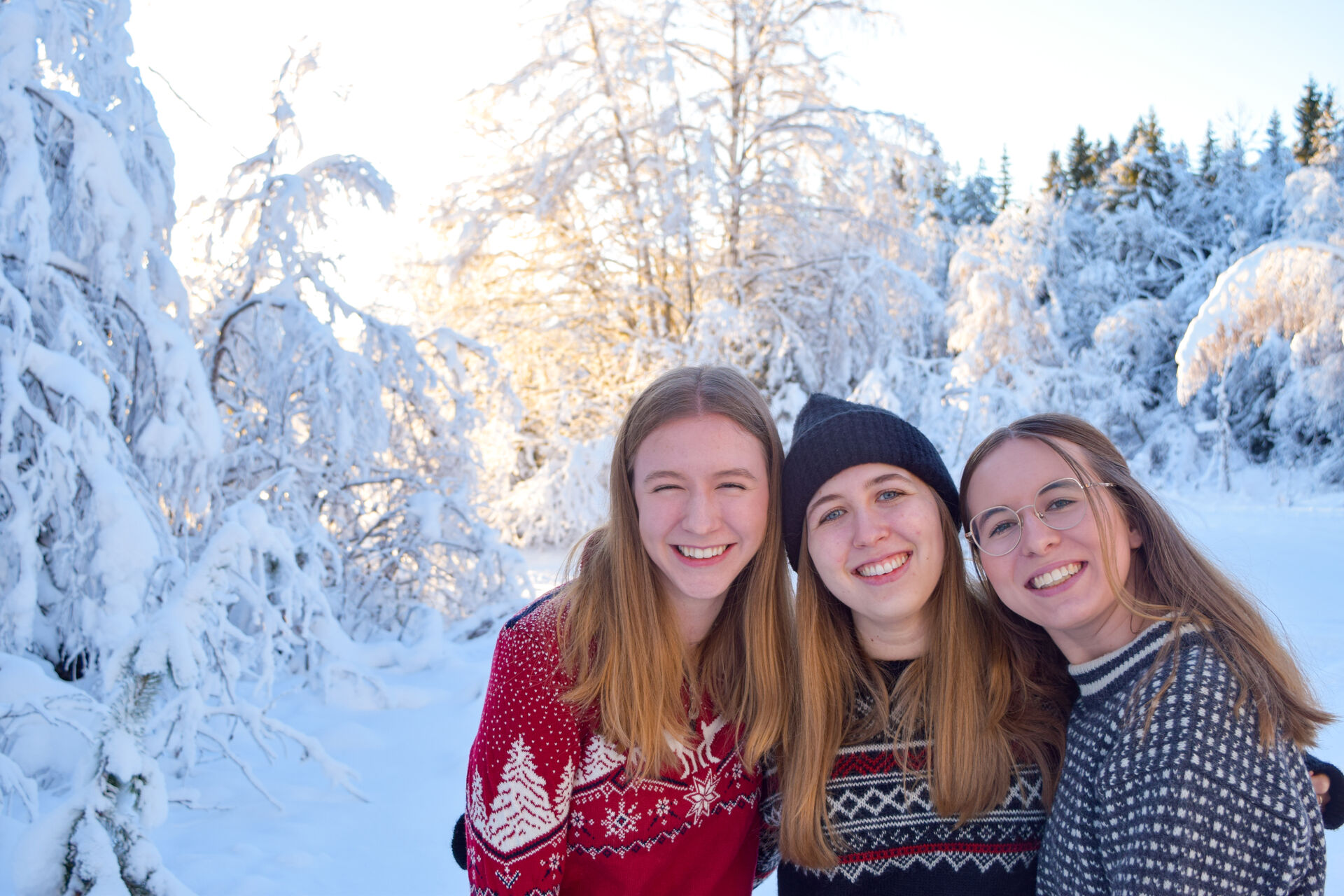 Female exchange students dressed in woollen sweaters posing in the snow covered forest