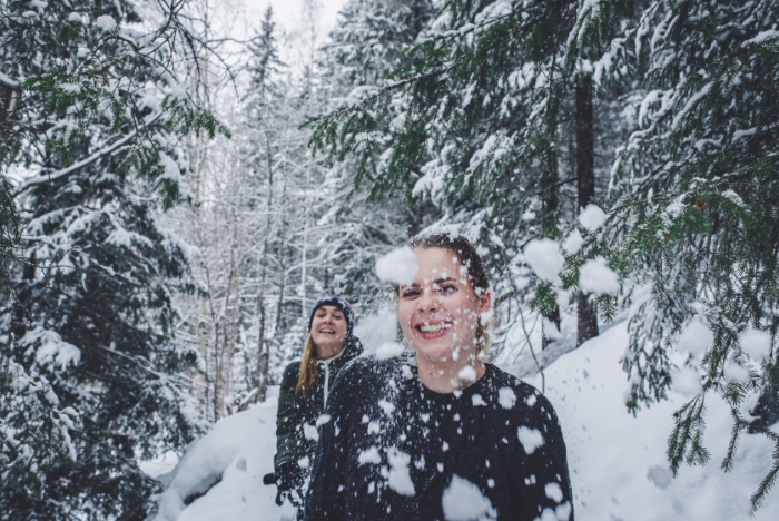 Female exchange students having fun throwing snow in the snow covered forest