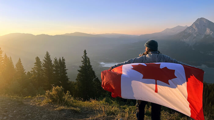 Student med et canadisk flagg på rygge som ser ut i horisonten. 