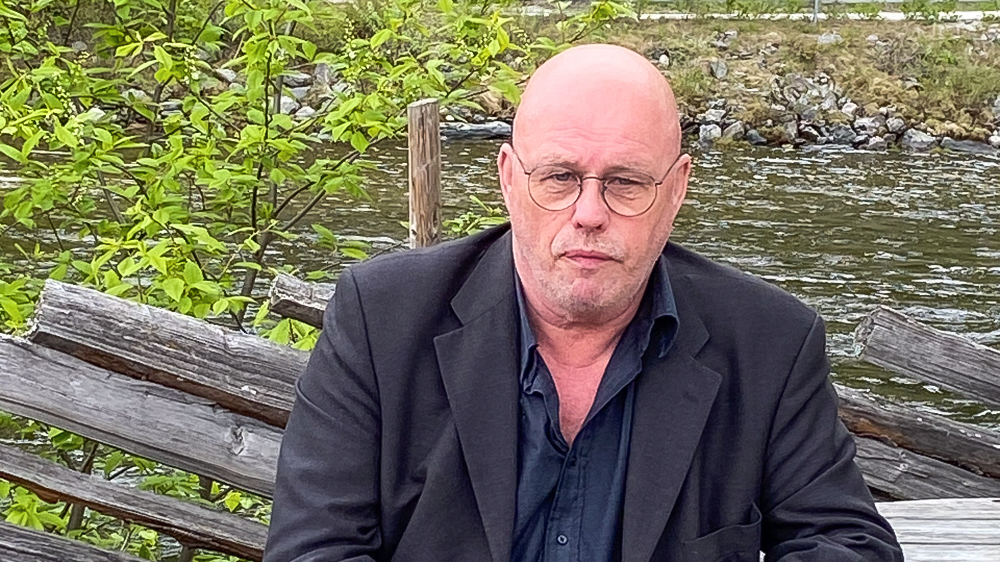 Anders Nordby on a bench with a fence end  a river in the background