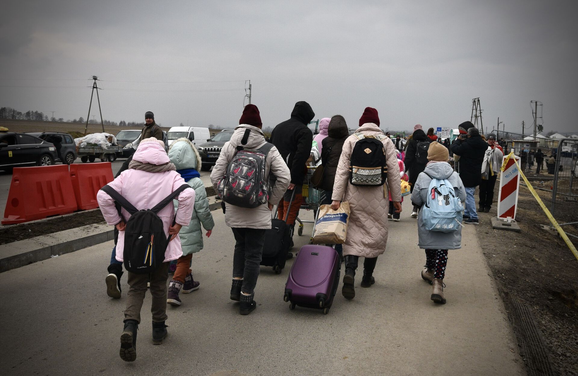 Ryggen på en flokk flyktninger med bagasje på vei mot grensen mellom Ukraina og Polen.