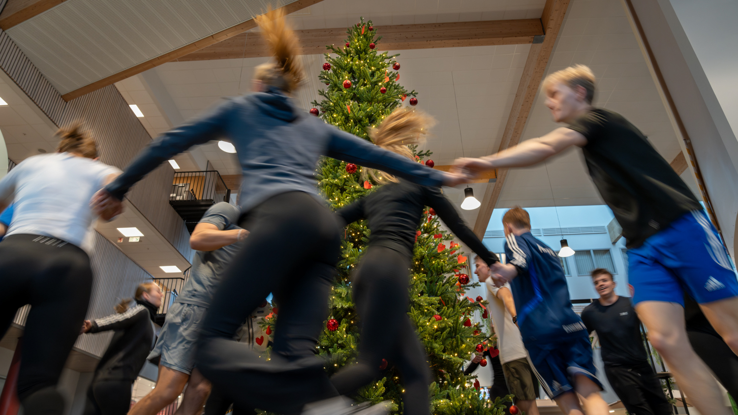 Ungdommer løper rundt et juletre i treningsutstyr