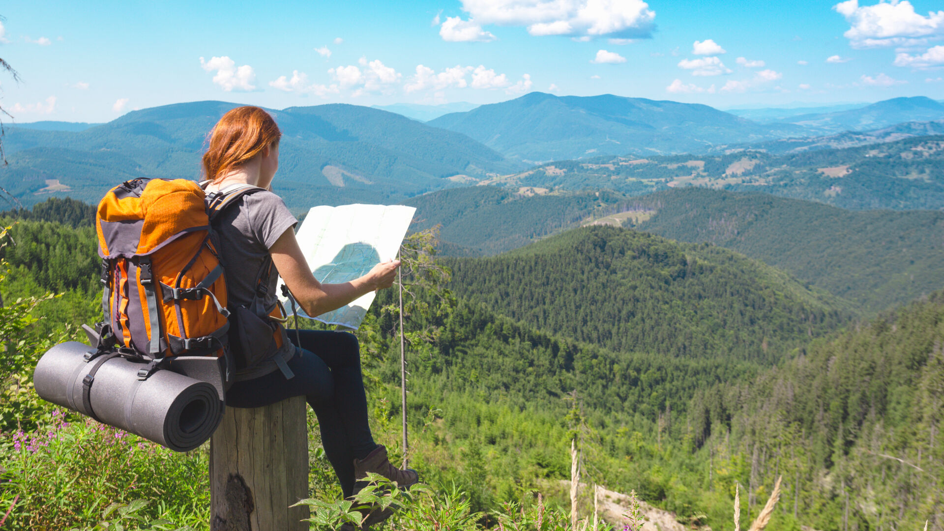 Jente sitter med kart og kikker utover norsk natur