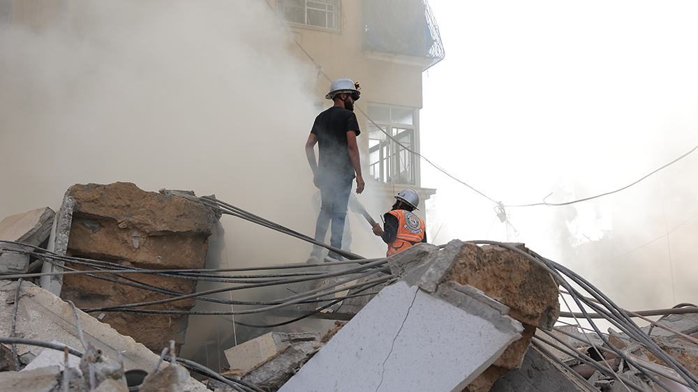 Redningsmannskaper står i ruinene av en utbombet boligblokk i Gaza (foto: Foto: Yousef Hammash/NRC) 