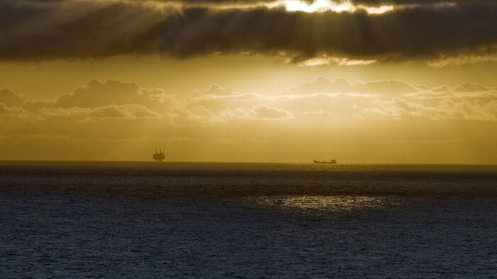 Bilde av oljeplattform på havet mot dramatisk himmel, sol og sky