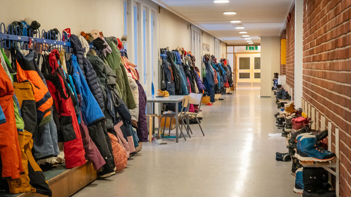 Bilde av en korridor på en skole med jakker hengende på knagger