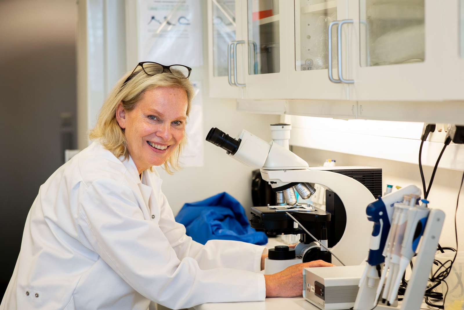 Elisabeth Kommisrud smilende ved mikroskop på lab.