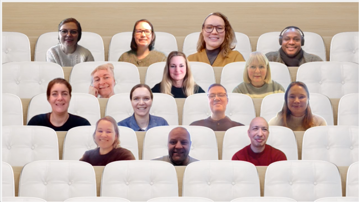 14 smilende personer i hvite konferansestoler