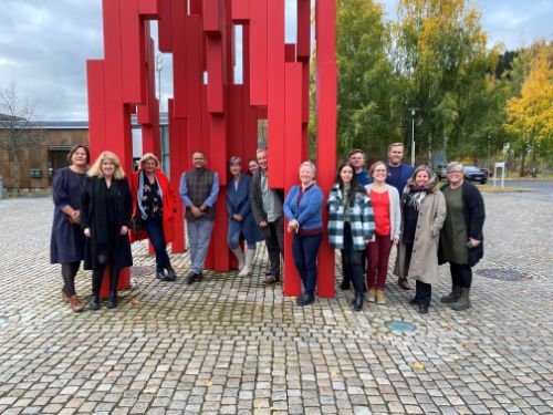 En gruppe på 15 seminardeltakerne foran den røde statua til HINN på Lillehammer