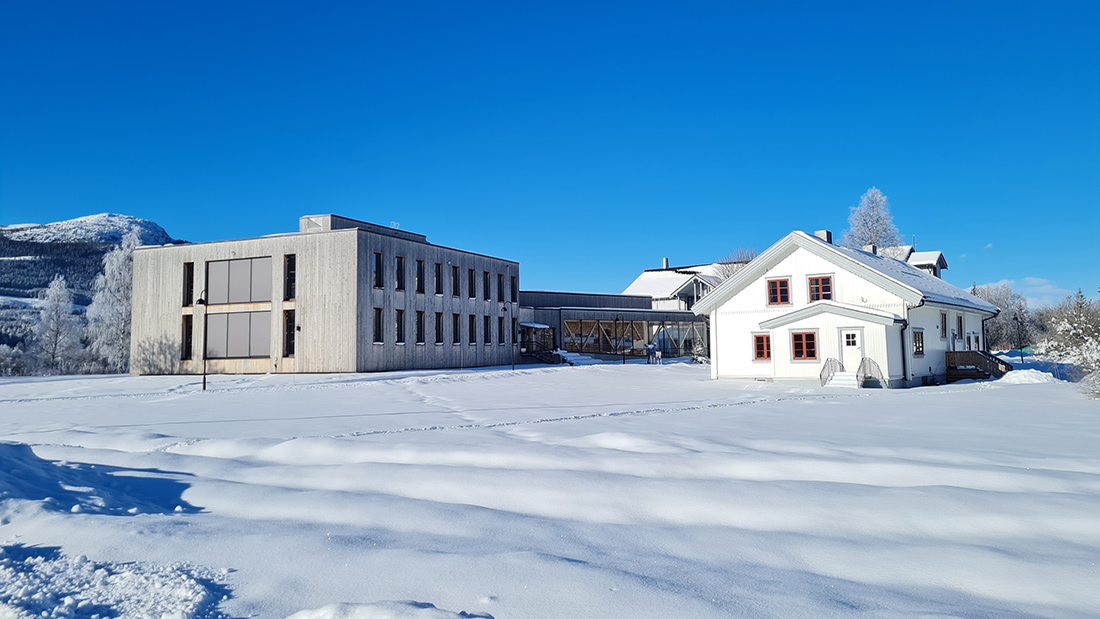 Vinterbilde av studiested Evensted i strålende solskinn med blå himmel. 