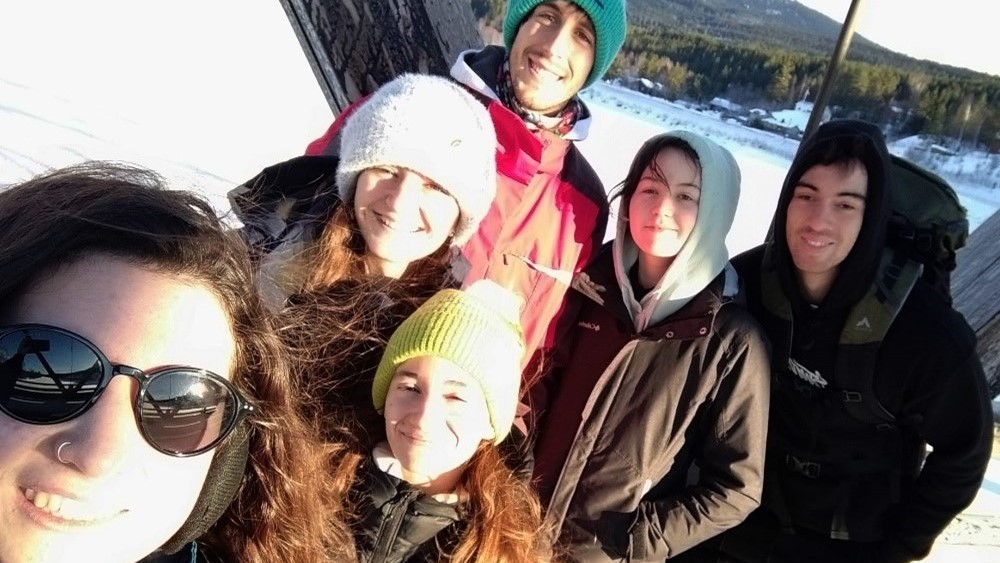 Seks studenter står på en bro og tar en selfie.
