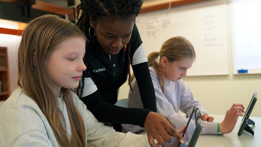  A teacher instructing two students on an iPad.