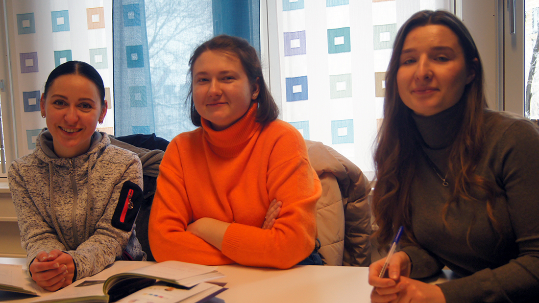 Tre smilende ukrainske studenter på et grupperom. 
