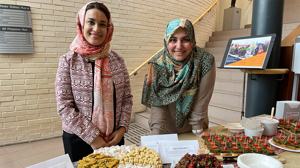 Bildet viser to internasjonale studenter som står på stand med lokal mat.