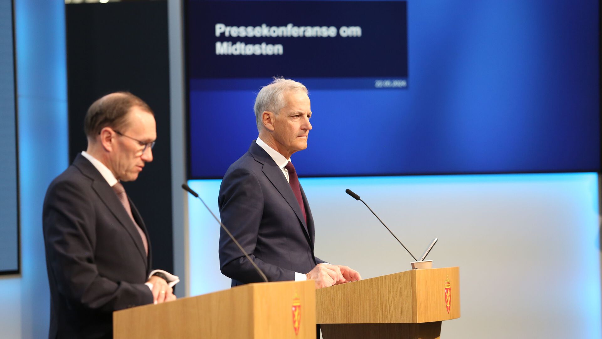 Utenriksministeren og statsministeren står bak hver sin talerstol med mikrofo. På veggen bak er en skjerm med teksten Pressekonferanse om Midtøsten