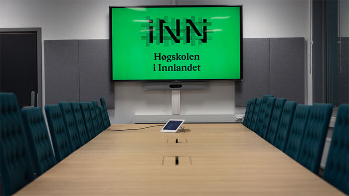 Bilde av møtebord med skjerm der HINN-logo vises.
