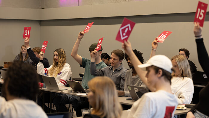 Studentrepresentantene i Studenttinget voterer ved å løfte rosa stemmeskilt med hvite detaljer