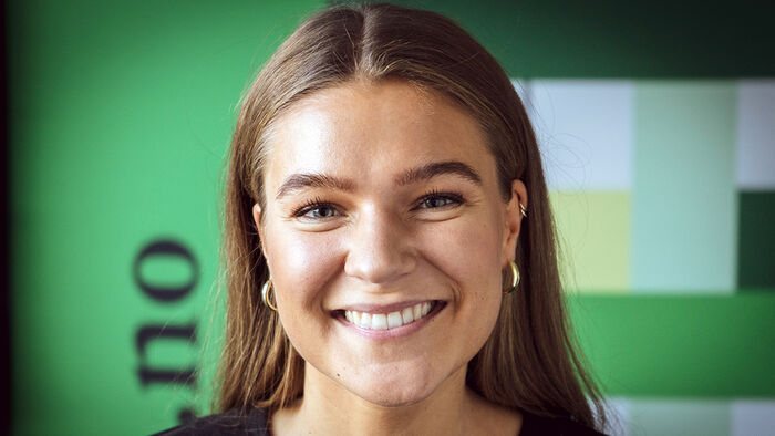 Portrettfoto Eirin Braatlund Fossberg foran en grønn bakgrunn. 