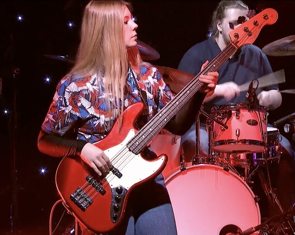 Bilde viser kvinnelig student som spiller bassgitar.